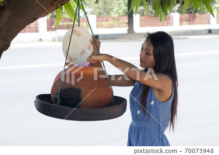 Woman taking water on a street Woman taking water on a street 70073948