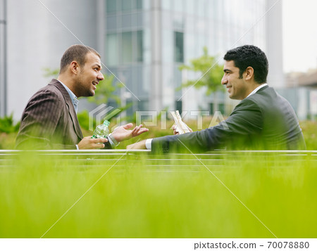 Two Business Men Enjoying Lunch Break Eating Sandwich Outdoors Two Business Men Enjoying Lunch Break Eating Sandwich Outdoors 70078880