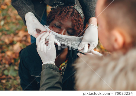 Two boys help a african girl in a autumn park 70083224