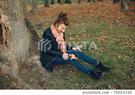 Girl with a broken leg in the autumn park 70083289