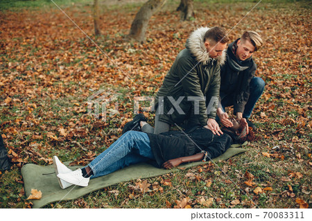 Two men in a autumn help a african girl 70083311