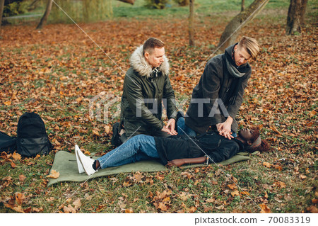 Two men in a autumn help a african girl 70083319