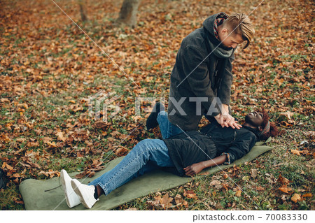 Man in a autumn park help african girl 70083330