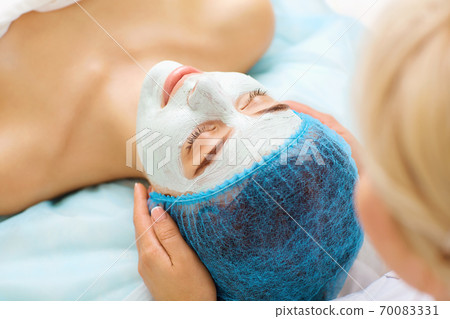 Cosmetologist makes beauty mask to a young woman. Cosmetologist makes beauty mask to a young woman. 70083331
