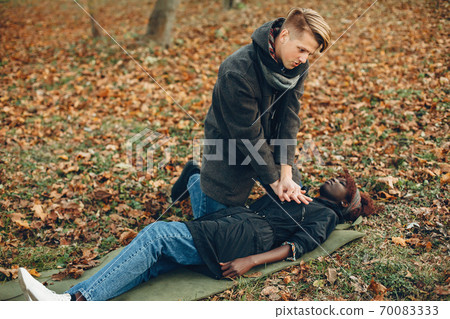 Man in a autumn park help african girl Man in a autumn park help african girl 70083333