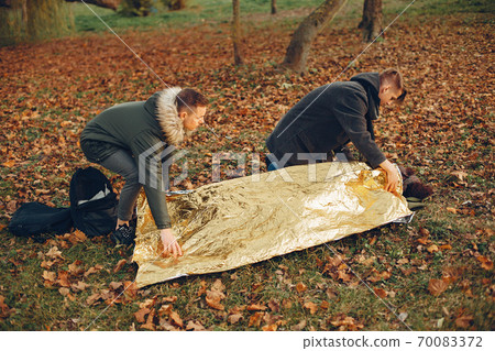 Two boys in a autumn park help a african girl Two boys in a autumn park help a african girl 70083372