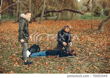 Two boys in a autumn park help a african girl Two boys in a autumn park help a african girl 70083449