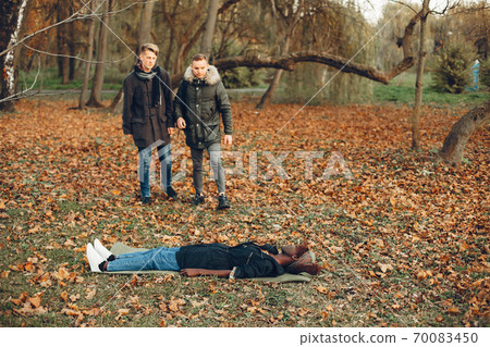 Two boys in a autumn park help a african girl 70083450