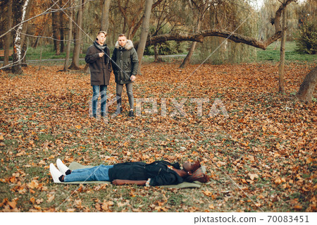 Two boys in a autumn park help a african girl 70083451