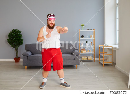 Funny fat boxer in sportswear is boxing in the room. Funny fat boxer in sportswear is boxing in the room. 70083972