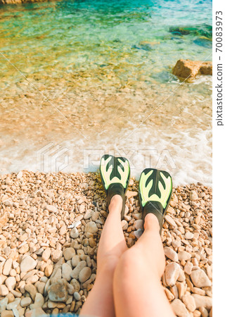 woman legs in flippers at beach sea on background woman legs in flippers at beach sea on background 70083973