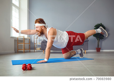Funny fat man doing yoga exercises in the room. Funny fat man doing yoga exercises in the room. 70083980