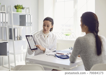 Woman patient visiting female doctor at clinic office. Medical work writes a prescription on a table in a hospital. 70084173