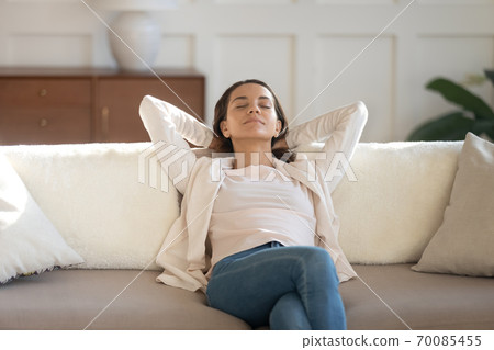 Peaceful young lady resting on comfy sofa enjoying calm moment Peaceful young lady resting on comfy sofa enjoying calm moment 70085455