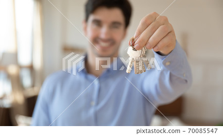 Smiling real estate agent giving you keys from purchased apartment 70085547