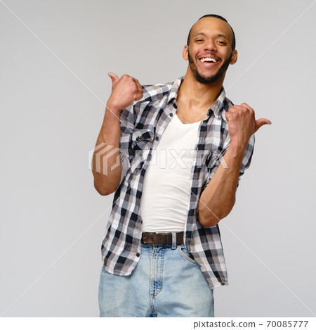african-american young man wearing casual shirt and showing thumbs up over light grey background african-american young man wearing casual shirt and showing thumbs up over light grey background 70085777