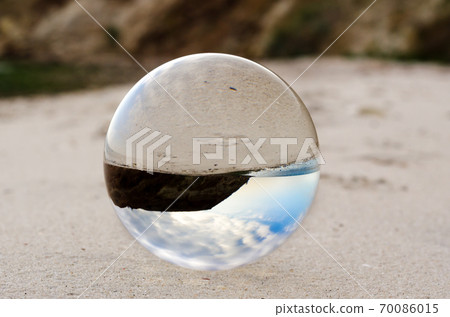 glass ball lens lies on the sand of the sea shore 70086015