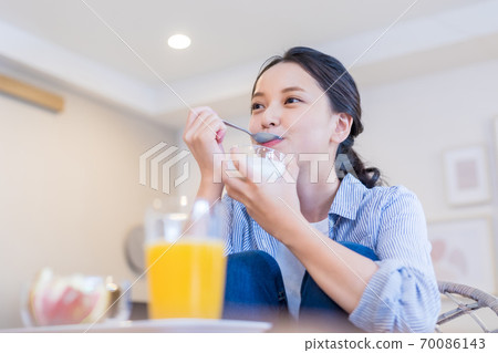 Young woman eating yogurt 70086143