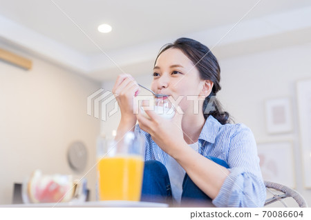 Young woman eating yogurt 70086604