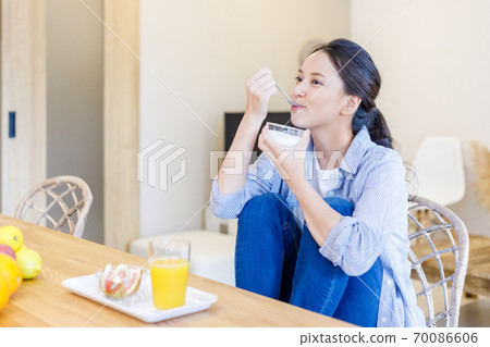 Young woman eating yogurt 70086606