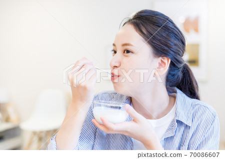 Young woman eating yogurt 70086607