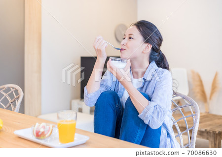 Young woman eating yogurt 70086630