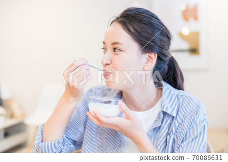 Young woman eating yogurt Young woman eating yogurt 70086631