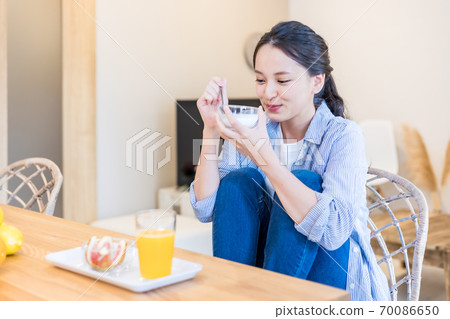 Young woman eating yogurt 70086650