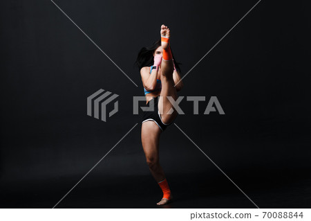 Sportsman muay thai woman boxer posing in training studio at black background. 70088844