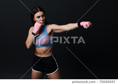 Sportsman muay thai woman boxer posing in training studio at black background. Sportsman muay thai woman boxer posing in training studio at black background. 70088845
