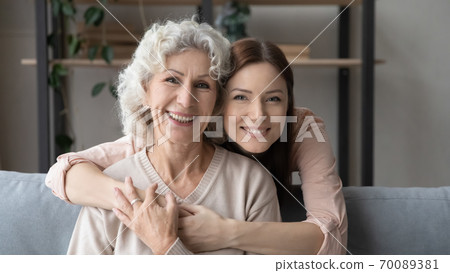 Head shot portrait young woman hugging mature mother from back 70089381
