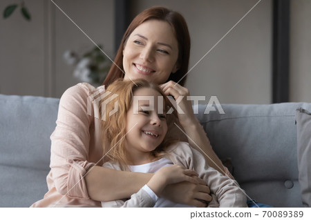 Smiling mother and adorable little daughter relaxing on couch together Smiling mother and adorable little daughter relaxing on couch together 70089389