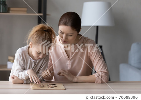 Pretty little girl and mother playing wooden board game Pretty little girl and mother playing wooden board game 70089390