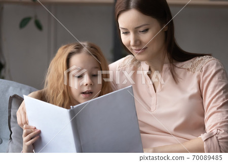 Close up loving mother and little girl reading book together 70089485