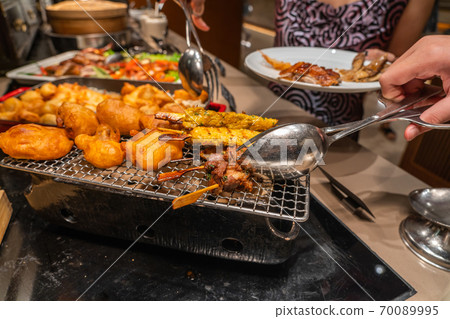 Human hand picking grilled chicken skewers in barbecue buffet 70089995
