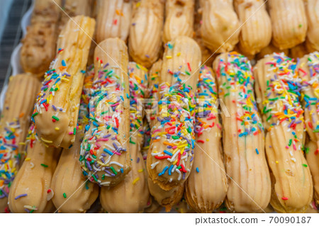 Pile of puffy choux stick with candy sprinkles at bakery 70090187