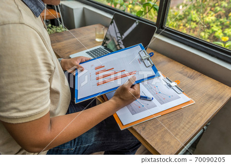 Asian freelancer hands holding diagram document at rustic workplace 70090205