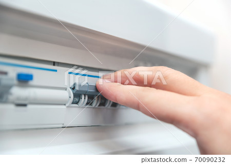 Man switches fuse in electrical switchboard Man switches fuse in electrical switchboard 70090232