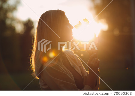 Happy young woman holds fall leaves in hand at autumn park 70090308