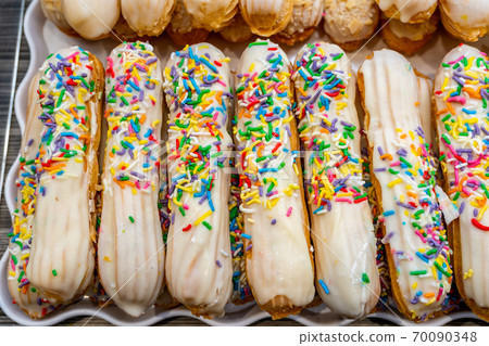 Pile of choux sticks pastry topped with colorful candy sprinkles 70090348
