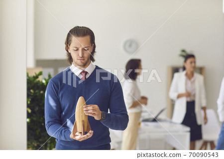 Office worker holding wooden rocket in hands in office Office worker holding wooden rocket in hands in office 70090543