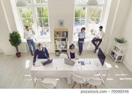 Serious young company employees preparing for corporate meeting in spacious office room Serious young company employees preparing for corporate meeting in spacious office room 70090546