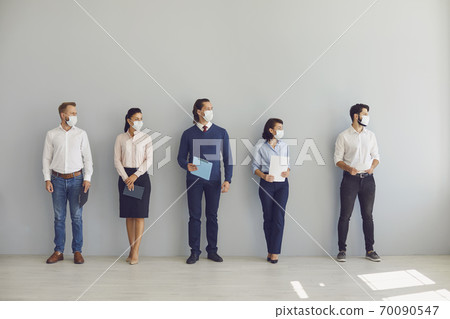 Job seekers in face masks waiting for job interview standing in corridor keeping safe distance Job seekers in face masks waiting for job interview standing in corridor keeping safe distance 70090547
