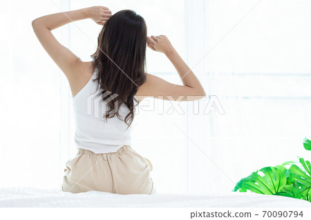 Asian women wake up happy and smile on white bed in bedroom. 70090794