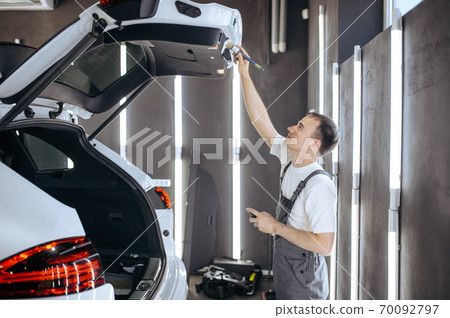 Worker with brush wipes car trunk door, detailing Worker with brush wipes car trunk door, detailing 70092797