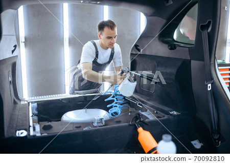 Worker sprays car trunk, dry cleaning, detailing 70092810