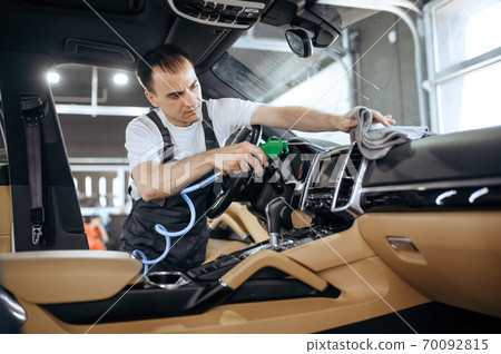 Worker with air gun cleans car air duct grating 70092815