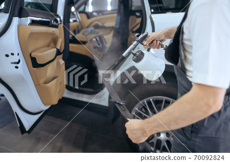 Worker sprays car seat belt, detailing 70092824