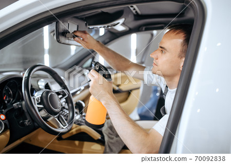 Worker with spray moisturizes car interior Worker with spray moisturizes car interior 70092838