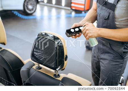 Worker applies agent on brush, car detailing 70092844
